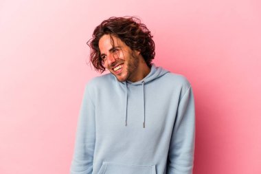 Pembe fırında izole edilmiş genç beyaz adam gülüyor ve gözlerini kapıyor, rahatlamış ve mutlu hissediyor..