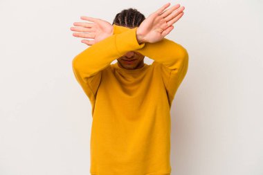 Genç Venezuelalı adam beyaz arka planda izole edilmiş iki kolu çapraz tutuyor, inkar kavramını koruyor.