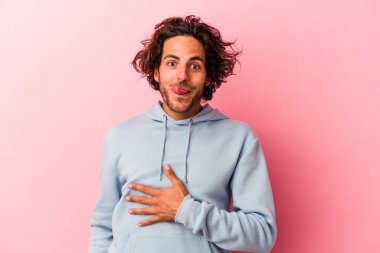 Pembe fırında izole edilmiş genç beyaz adam karnına dokunuyor, nazikçe gülümsüyor, yemek yiyor ve tatmin oluyor..