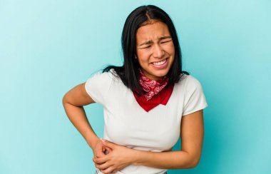 Genç Venezuelalı bir kadın mavi arka planda karaciğer ağrısı ve mide ağrısı çekiyor..