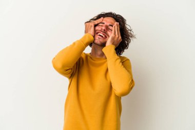 Beyaz arka planda izole olmuş genç beyaz bir adam ellerini başının üstünde tutarak neşeyle gülüyor. Mutluluk kavramı.