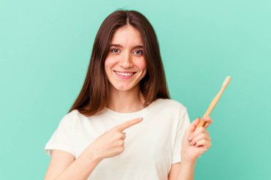 Mavi arka planda diş fırçası tutan beyaz bir kadın.