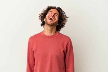 Beyaz arka planda izole edilmiş genç beyaz adam gevşemiş ve mutlu bir şekilde gülüyor, boynunda dişlerini gösteriyor..