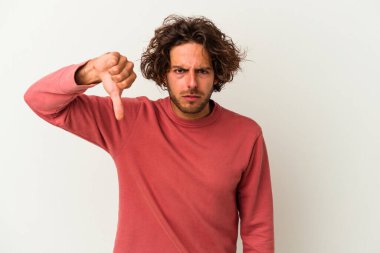 Beyaz arka planda izole edilmiş genç beyaz bir adam baş parmağını aşağı gösteriyor ve hoşlanmadığını ifade ediyor..