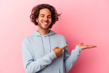 Pembe fırında izole edilmiş genç beyaz adam palmiye ağacında bir kopya alanı tutarken heyecanlanıyor..