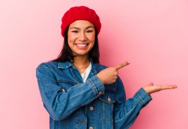 Genç Venezuelalı bir kadın pembe arka planda izole edilmiş..