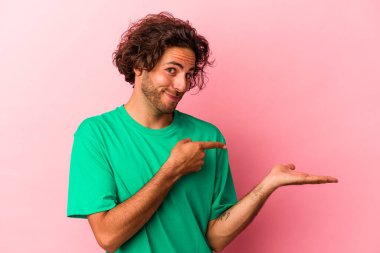 Pembe fırında izole edilmiş genç beyaz adam palmiye ağacında bir kopya alanı tutarken heyecanlanıyor..