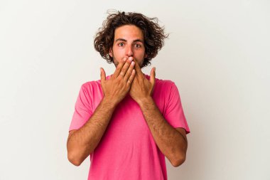 Beyaz arka planda izole edilmiş genç beyaz adam şok olmuş, ağzı ellerle kaplanmış, yeni bir şey keşfetmeye hevesli..