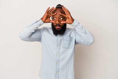 Pembe arka planda izole edilmiş sakallı Afrikalı Amerikalı bir adam bir başarı fırsatı bulmak için gözlerini açık tutuyor..