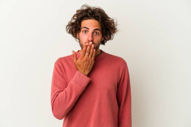 Beyaz arka planda izole edilmiş genç beyaz adam şok olmuş, ağzı ellerle kaplanmış, yeni bir şey keşfetmeye hevesli..