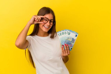 Sarı arka planda izole edilmiş banknotlar tutan beyaz bir kadın heyecanlı..