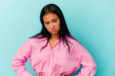Genç Venezuelalı bir kadın mavi arka planda soyutlanmış üzgün, ciddi bir yüz, mutsuz ve hoşnutsuz.
