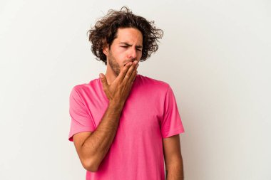 Beyaz arka planda izole edilmiş genç beyaz adam esniyor. Ağzı eliyle kapatan yorgun bir hareket sergiliyor..