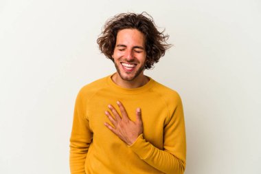 Beyaz arka planda izole genç beyaz adam yüksek sesle gülüyor elini göğsüne koyuyor..