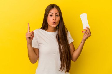 Sarı arka planda bir kompres tutan beyaz bir kadın. Harika bir fikri var. Yaratıcılık kavramı..