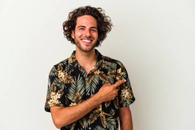 Beyaz arka planda izole edilmiş genç beyaz bir adam gülümsüyor ve boş alanda bir şeyler gösteriyor..