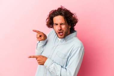 Pembe fırında izole edilmiş genç beyaz bir adam işaret parmaklarıyla fotokopi alanını işaret ederek heyecan ve arzusunu ifade ediyor..