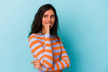 Mavi arka planda izole edilmiş genç beyaz kadın rahatça fotokopi odasına bakan bir şey düşünüyor..