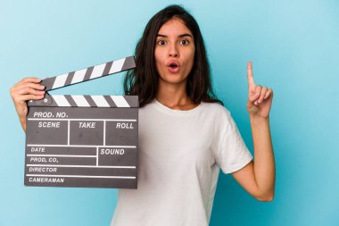 Kafkasyalı genç bir kadın mavi arka planda izole edilmiş bir alçıpan tutuyor. Harika bir fikri var, yaratıcılık kavramı..