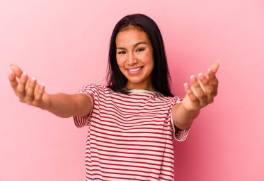 Pembe arka planda izole edilmiş genç Venezuelalı kadın kameraya sarıldığı için kendinden emin..