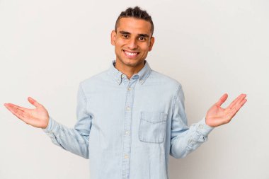 Venezuelalı genç bir adam beyaz arka planda izole edilmiş. Sorgulama sırasında omuz silkiyor ve şüphe ediyor..