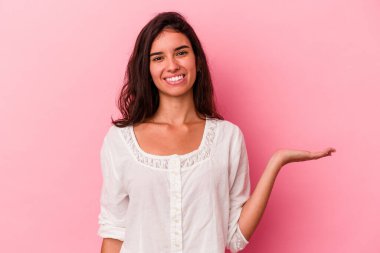 Pembe arka planda izole edilmiş genç beyaz kadın bir avuç içinde fotokopi alanı ve belinde bir el daha gösteriyor..