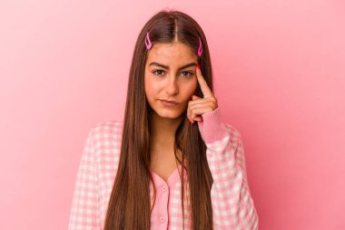 Pembe arka planda izole edilmiş beyaz bir kadın şakağı parmağıyla işaret ediyor, düşünüyor ve bir göreve odaklanıyor..