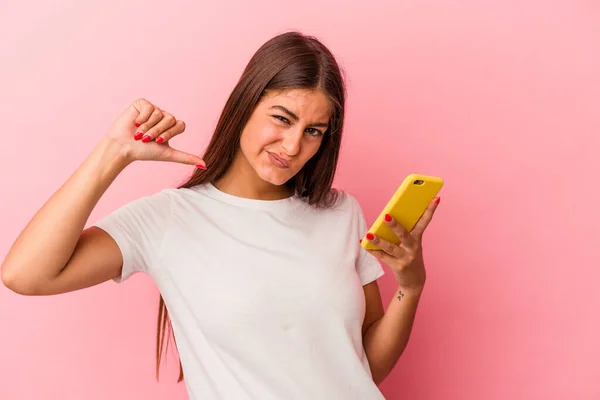 年轻的高加索女人拿着一部粉色背景的手机 感到自豪和自信 可以学习 — 图库照片