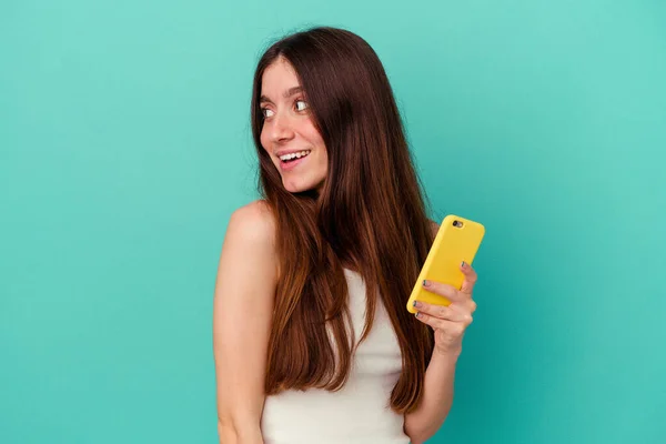 Joven Mujer Caucásica Sosteniendo Teléfono Móvil Aislado Sobre Fondo Azul —  Fotos de Stock