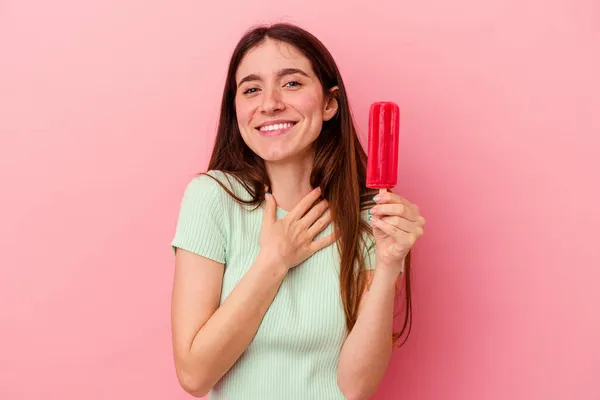 青い背景で隔離されたアイスクリームを持っている若い白人女性は大声で手を胸に保つことを笑う — ストック写真