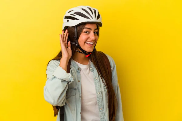若いです学生Caucasian女性身に着けていますAバイクヘルメット隔離された上に黄色の背景を聞いてみてくださいゴシップ — ストック写真