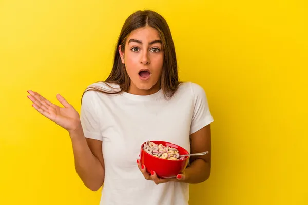 Jovem Caucasiana Segurando Cereais Isolados Fundo Amarelo Surpreso Chocado — Fotografia de Stock