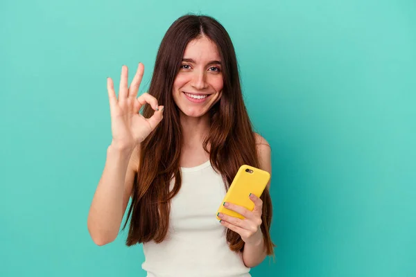 Giovane Donna Caucasica Possesso Telefono Cellulare Isolato Sfondo Blu Allegro — Foto Stock