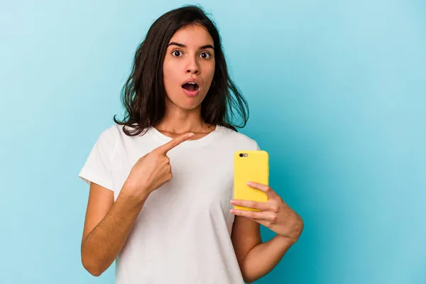 Jovem Caucasiana Segurando Telefone Celular Isolado Fundo Azul Apontando Para — Fotografia de Stock