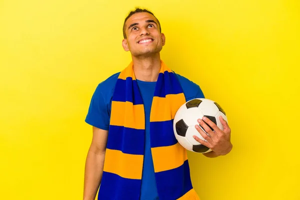 Νεαρός Άνδρας Από Βενεζουέλα Βλέποντας Ποδόσφαιρο Απομονωμένο Κίτρινο Φόντο Ονειρεύεται — Φωτογραφία Αρχείου