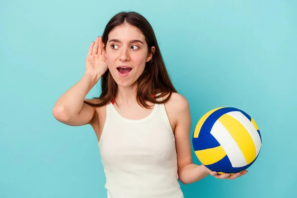 Молода Біла Жінка Грає Волейбол Ізольовано Синьому Фоні Намагаючись Слухати — стокове фото