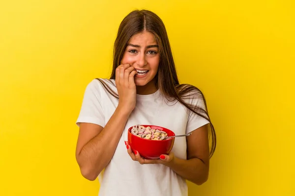 Mulher Branca Jovem Segurando Cereais Isolados Fundo Amarelo Mordendo Unhas — Fotografia de Stock