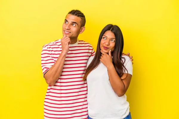 Jong Latijn Paar Geïsoleerd Gele Achtergrond Kijken Zijwaarts Met Twijfelachtige — Stockfoto