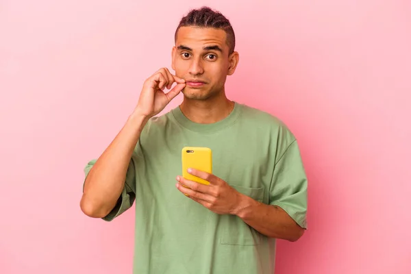 Młody Wenezuelczyk Trzymający Telefon Komórkowy Różowym Tle Palcami Ustach Trzymający — Zdjęcie stockowe