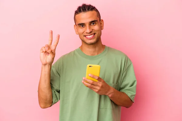 Młody Wenezuelczyk Trzymający Telefon Komórkowy Odizolowany Różowym Tle Pokazujący Numer — Zdjęcie stockowe