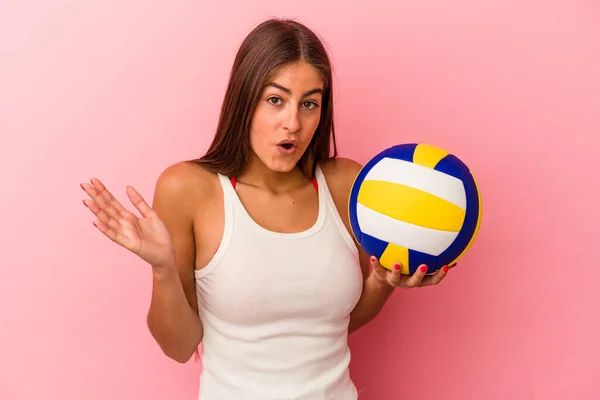 若いですCaucasian女性保持Aバレーボールボール隔離上のピンクの背景驚きとショック — ストック写真