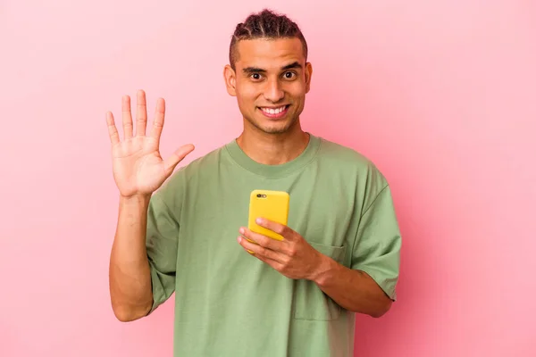 Joven Venezolano Sosteniendo Teléfono Móvil Aislado Sobre Fondo Rosa Sonriente —  Fotos de Stock