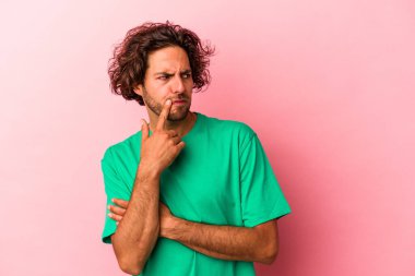 Pembe fırında izole edilmiş genç beyaz bir adam şüpheli ve şüpheci bir ifadeyle yana bakıyor..