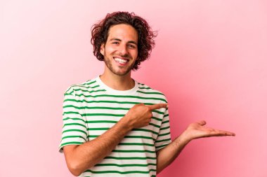 Pembe fırında izole edilmiş genç beyaz adam palmiye ağacında bir kopya alanı tutarken heyecanlanıyor..