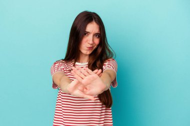 Mavi arka planda izole edilmiş genç beyaz kadın elini uzatmış, dur işareti göstererek seni engelliyor..