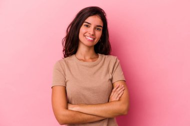Pembe arka planda soyutlanmış genç beyaz kadın kendini güvende hissediyor, kararlılıkla kollarını kavuşturuyor..