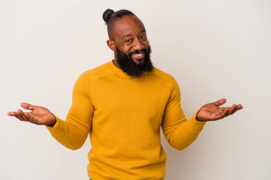 Pembe arka planda sakallı Afrikalı Amerikalı adam kollarıyla ölçek oluşturuyor, mutlu ve kendinden emin hissediyor..
