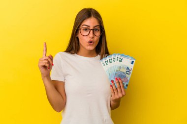 Sarı arka planda izole edilmiş banknotlar tutan beyaz bir kadın. Harika bir fikir, yaratıcılık kavramı var..