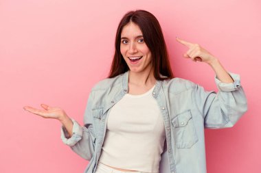 Pembe arka planda izole edilmiş beyaz bir kadın elinde bir ürün tutuyor..