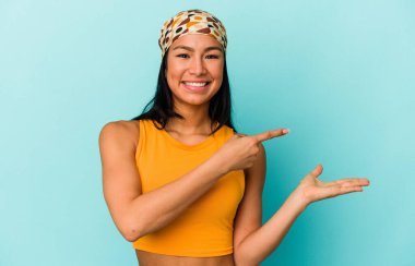 Venezuelalı genç bir kadın mavi arka planda izole edilmiş..